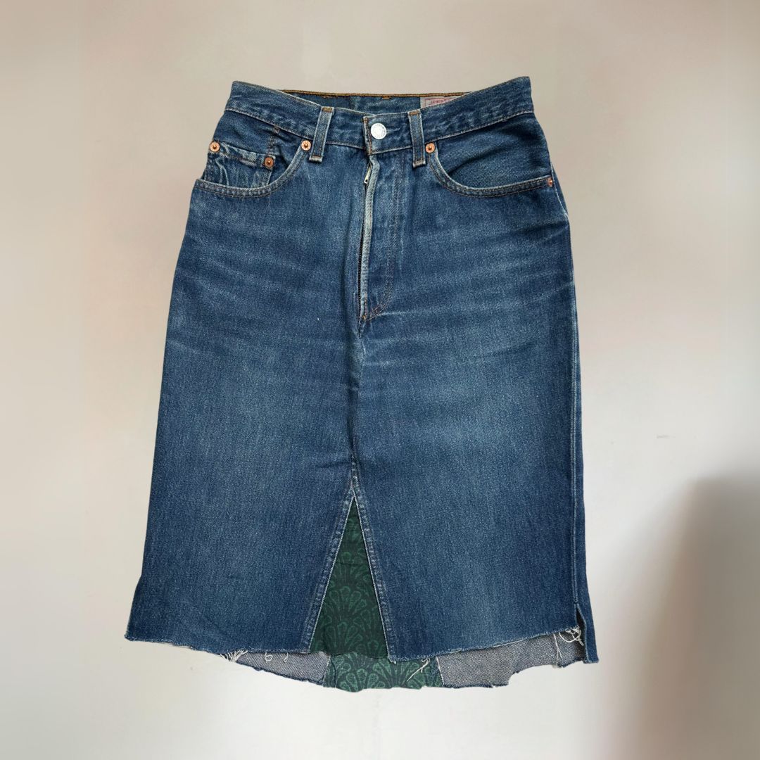A Levi's denim women's skirt with a knee-length cut, five pockets, and fabric paneling on the end.